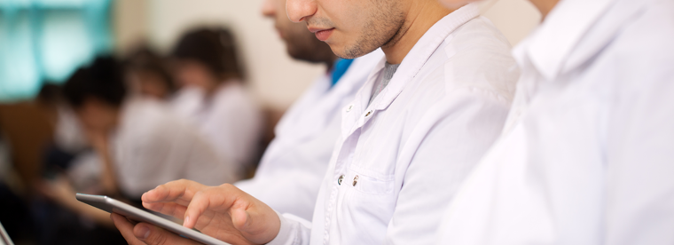 Medical professionals in white coats looking at tablet in clinical setting