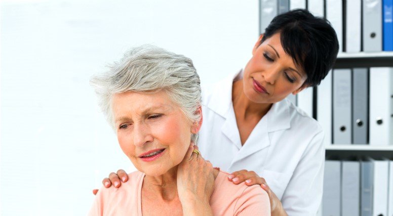 Health professional evaluates woman with neck pain
